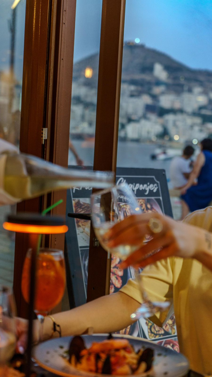 White wine pour with Sarandë hills in the window